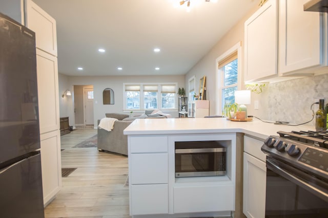 kitchen with recessed lighting, light countertops, light wood-style flooring, decorative backsplash, and appliances with stainless steel finishes