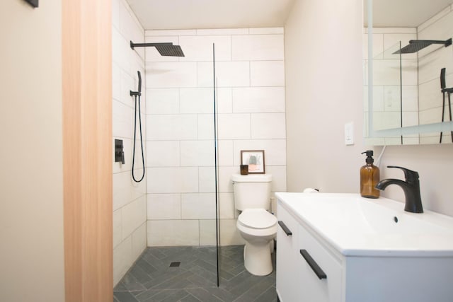 bathroom with toilet, tiled shower, and vanity