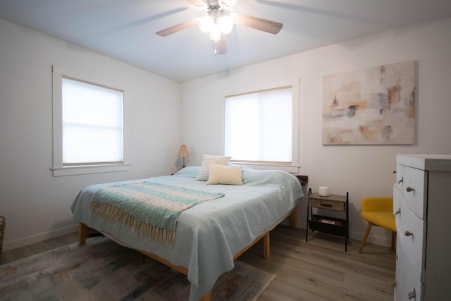 bedroom with ceiling fan, light wood-type flooring, and baseboards