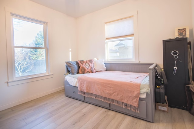 bedroom featuring multiple windows, baseboards, and wood finished floors