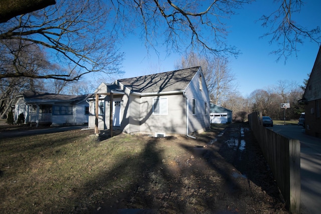 view of property exterior featuring roof with shingles, a lawn, and driveway