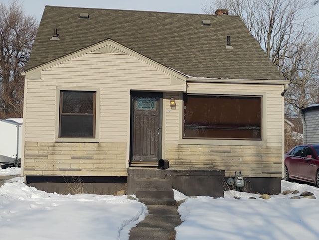 view of front facade featuring stone siding and a shingled roof