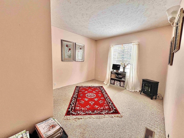 carpeted office space with a wood stove, visible vents, and a textured ceiling