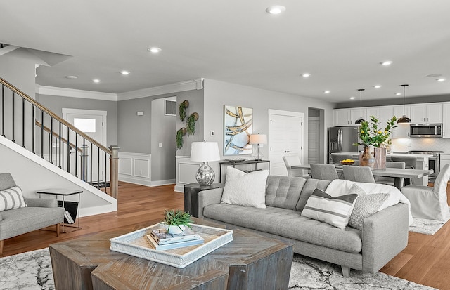 living area with light wood finished floors, stairs, ornamental molding, and recessed lighting