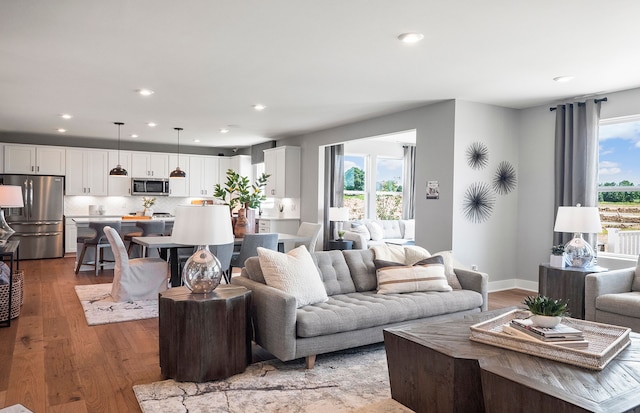 living area featuring recessed lighting, plenty of natural light, light wood-style flooring, and baseboards