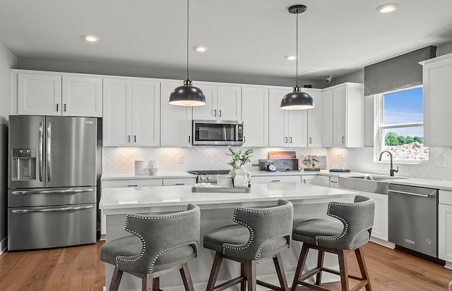 kitchen with white cabinets, appliances with stainless steel finishes, light countertops, and wood finished floors