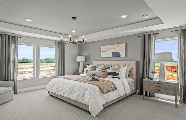 carpeted bedroom featuring multiple windows, baseboards, a raised ceiling, and a notable chandelier