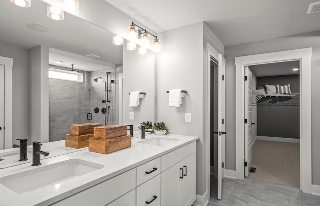 full bath featuring double vanity, a spacious closet, a sink, and a shower stall