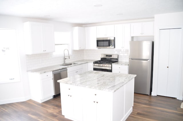 kitchen with stainless steel appliances, dark wood finished floors, a center island, and a sink