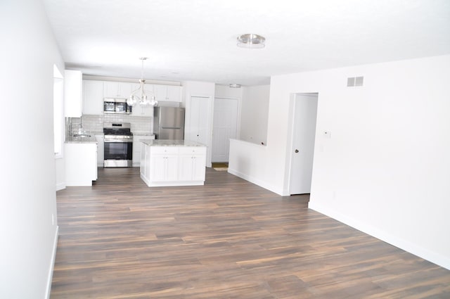 kitchen featuring a kitchen island, dark wood-type flooring, stainless steel appliances, white cabinetry, and backsplash