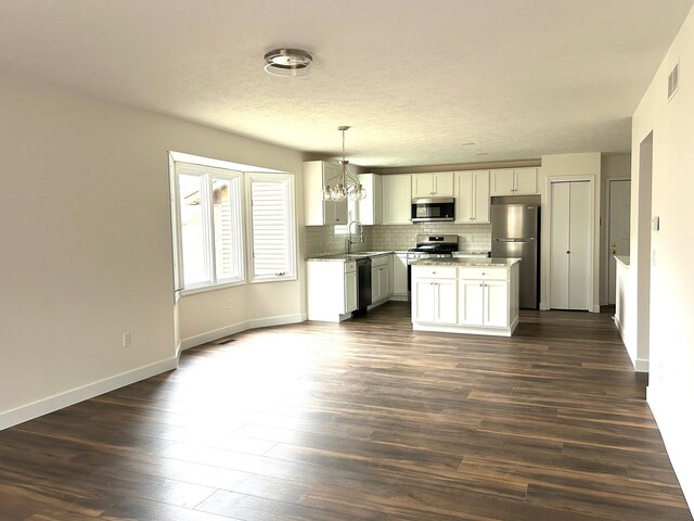 kitchen featuring visible vents, dark wood-type flooring, a sink, stainless steel appliances, and backsplash