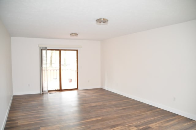 unfurnished room with dark wood-type flooring and baseboards