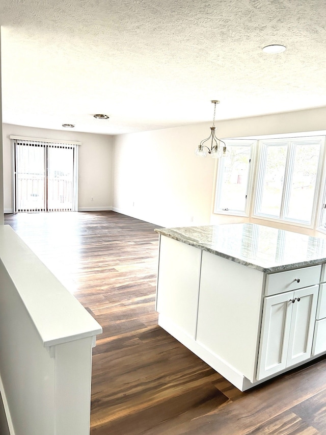 kitchen with dark wood-style floors, a center island, decorative light fixtures, and a textured ceiling