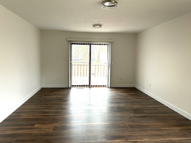 unfurnished room featuring dark wood-style floors, a textured ceiling, and baseboards