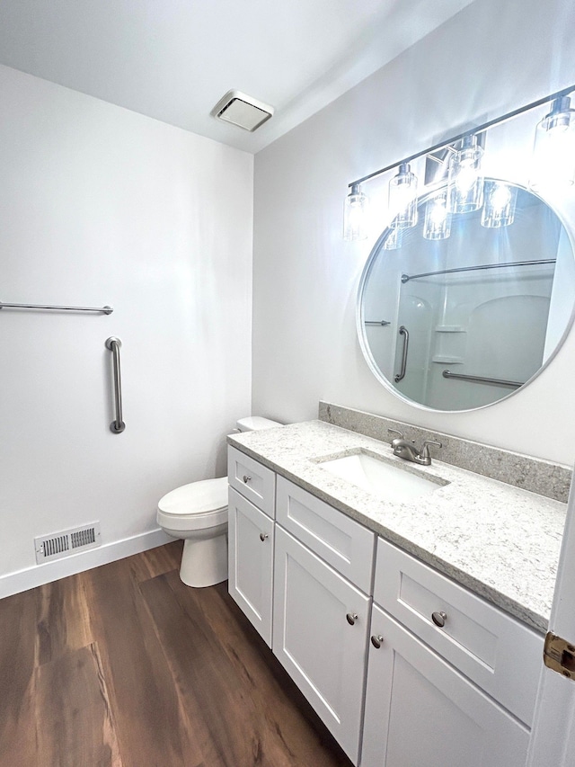 bathroom with a shower, visible vents, toilet, vanity, and wood finished floors