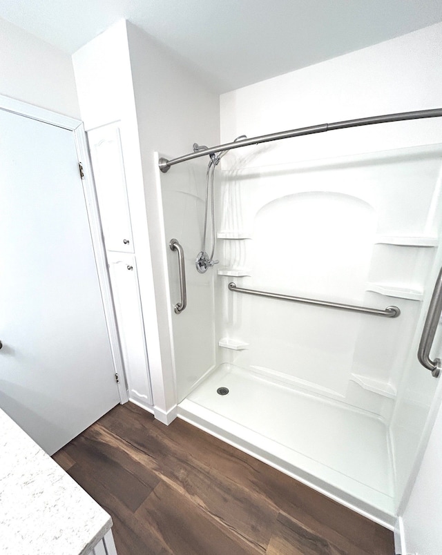 bathroom with a shower stall and wood finished floors