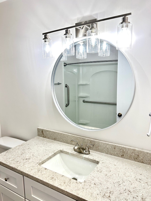 bathroom featuring toilet, an enclosed shower, and vanity