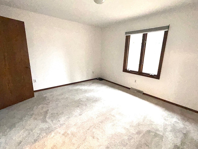 unfurnished room with carpet floors, baseboards, and visible vents