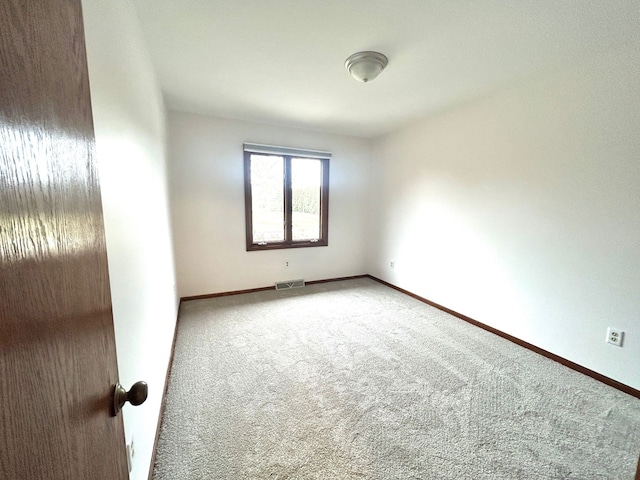 unfurnished room with carpet, visible vents, and baseboards