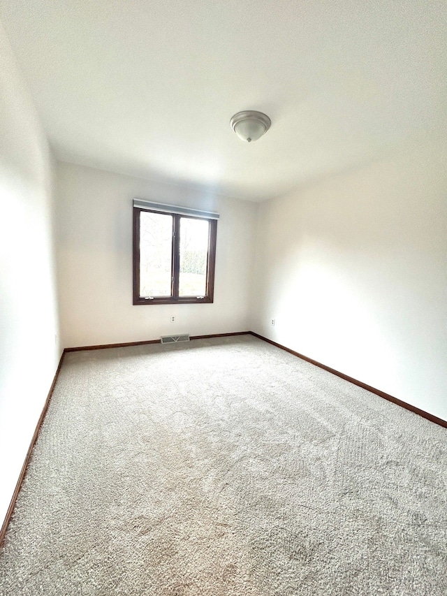 carpeted empty room featuring baseboards and visible vents