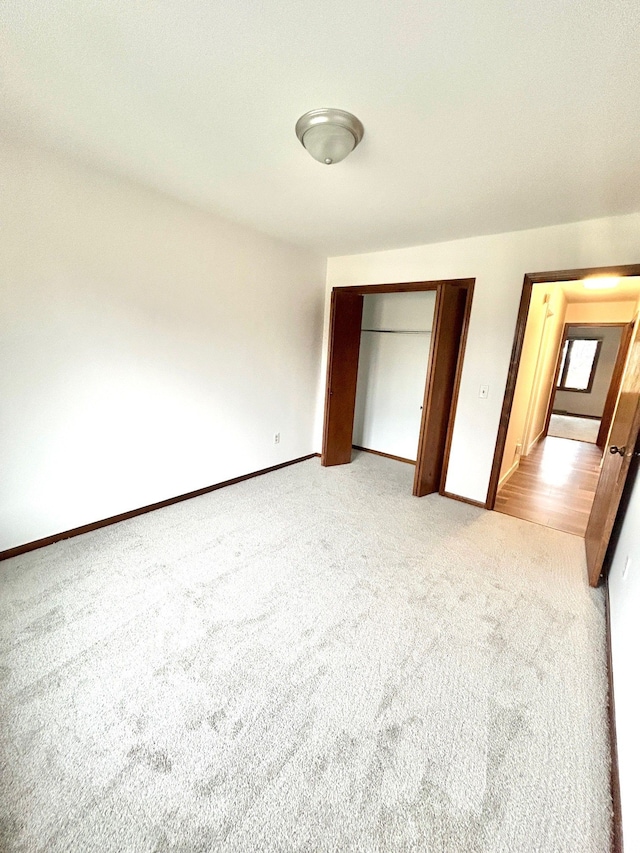 unfurnished bedroom featuring a closet, light carpet, and baseboards