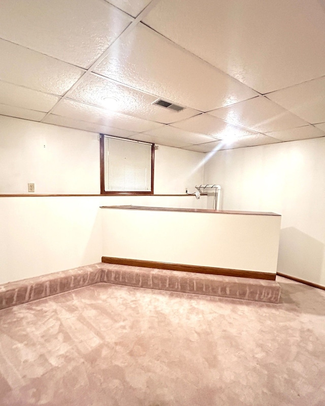 finished basement with baseboards, visible vents, a drop ceiling, and carpet flooring