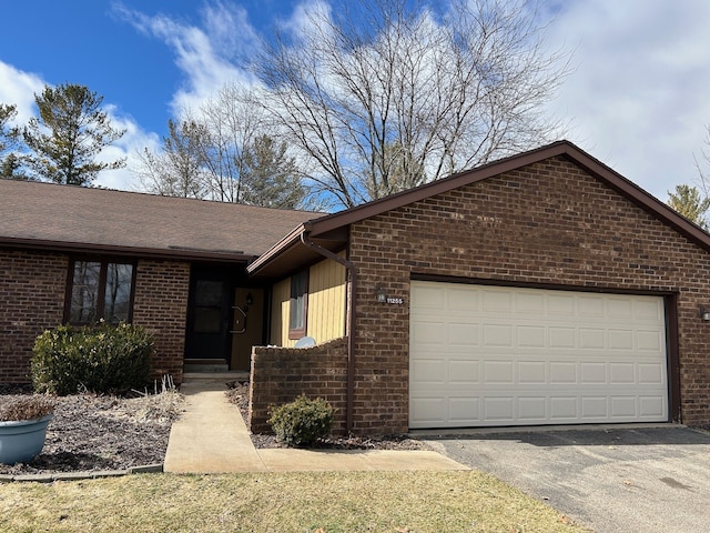 single story home featuring a shingled roof, brick siding, driveway, and an attached garage