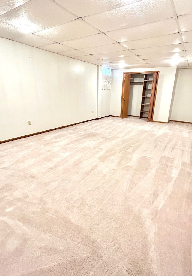 finished basement featuring baseboards, light carpet, and a drop ceiling