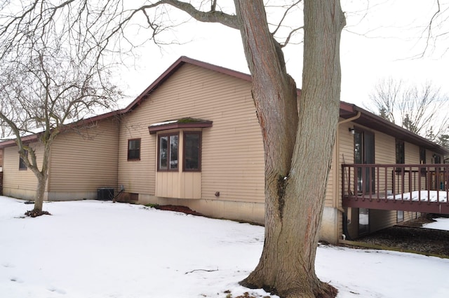 view of snow covered exterior with a deck and cooling unit