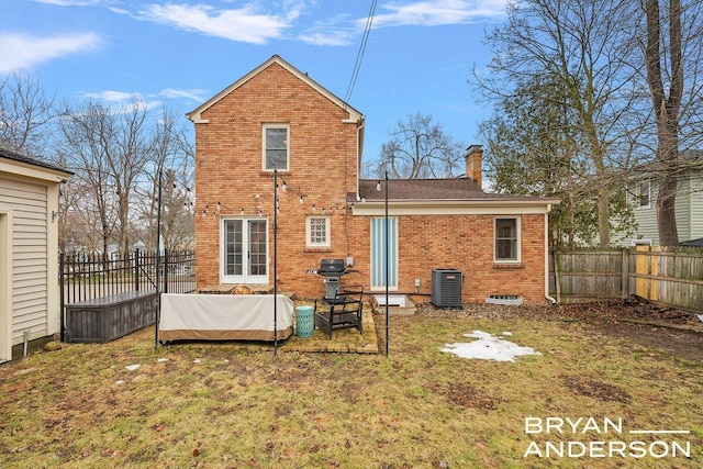 back of property featuring brick siding, a yard, a chimney, central air condition unit, and fence