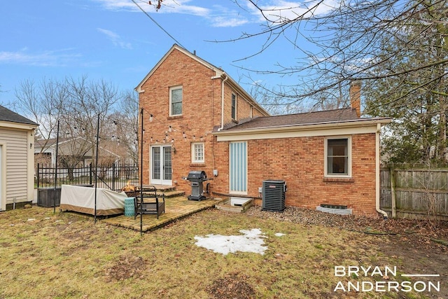 back of house featuring central AC, brick siding, a chimney, and fence