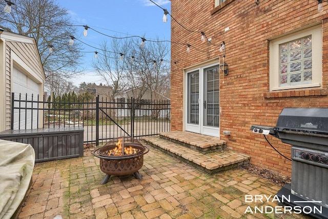 view of patio with french doors, fence, and a fire pit