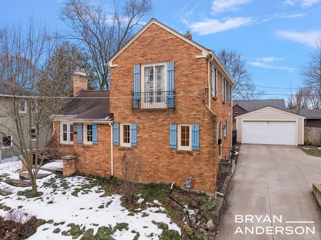 view of side of property with brick siding, a chimney, a detached garage, and an outdoor structure