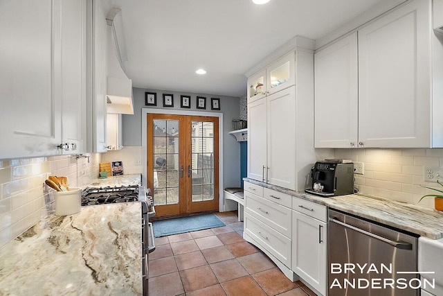 kitchen with light stone counters, french doors, light tile patterned floors, appliances with stainless steel finishes, and white cabinets