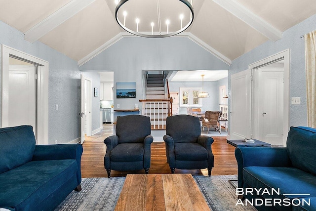 living room with a chandelier, a textured wall, lofted ceiling with beams, wood finished floors, and stairs