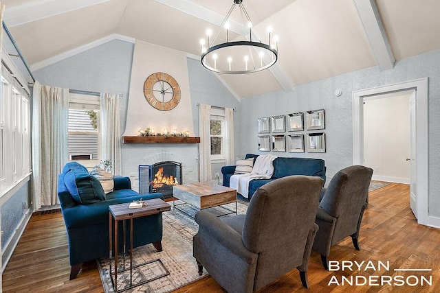 living room with a notable chandelier, vaulted ceiling with beams, a fireplace, and wood finished floors