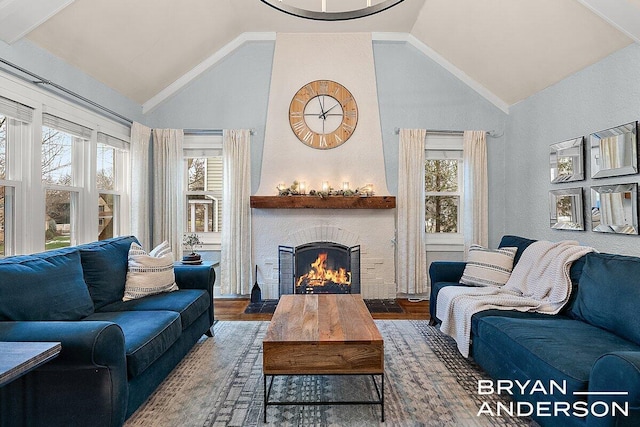 living area with lofted ceiling, a large fireplace, and wood finished floors