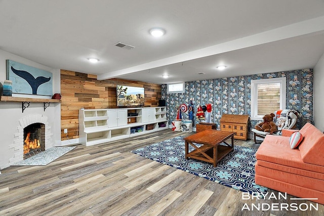 living area featuring a healthy amount of sunlight, a brick fireplace, visible vents, and wood finished floors