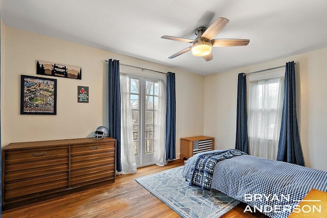 bedroom with light wood-style floors, multiple windows, and a ceiling fan