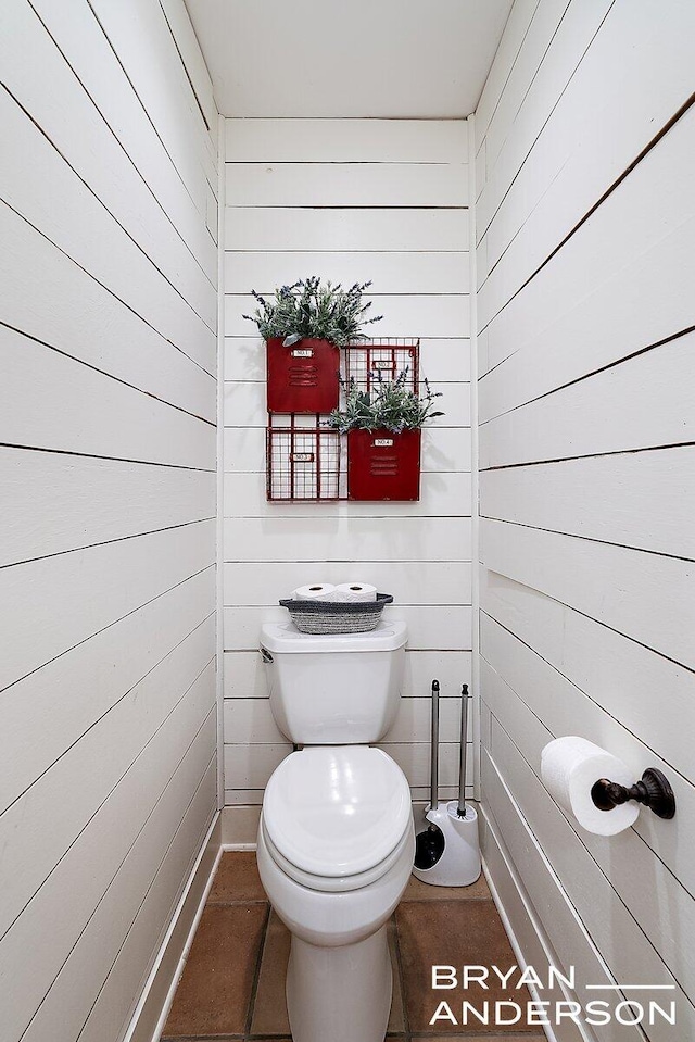 bathroom featuring wooden walls and toilet