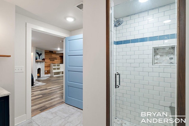 full bath featuring wooden walls, a shower stall, a fireplace, and visible vents