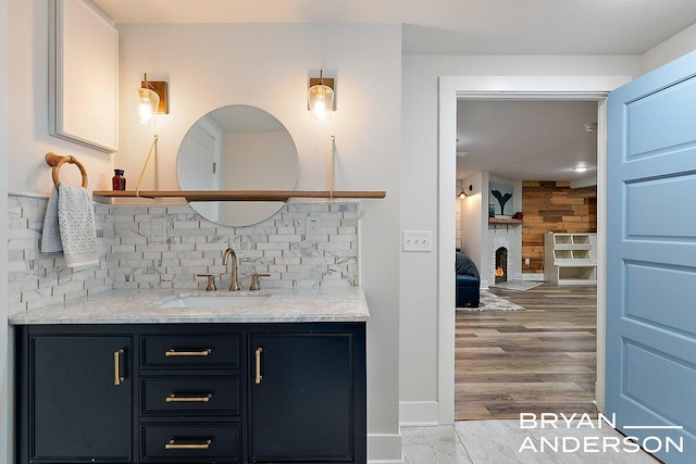 bar with tasteful backsplash, wood walls, a sink, wood finished floors, and a lit fireplace