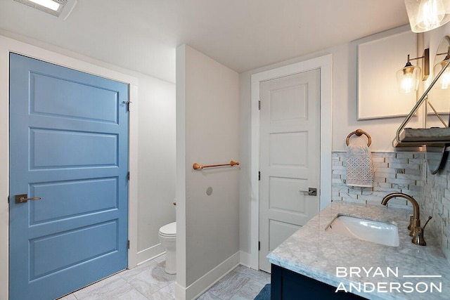 bathroom featuring toilet, vanity, visible vents, baseboards, and tasteful backsplash