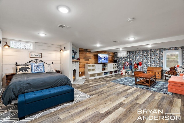 bedroom featuring visible vents, a fireplace, multiple windows, and wood finished floors