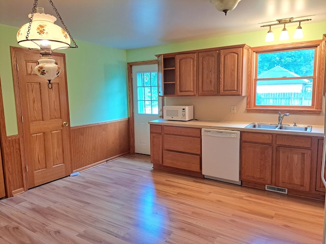 kitchen with visible vents, light wood-style flooring, wainscoting, a sink, and white appliances