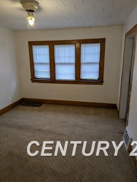 carpeted empty room featuring baseboards and visible vents