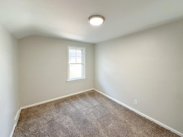 empty room with vaulted ceiling, carpet, and baseboards