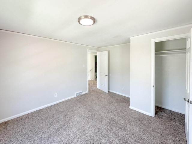 unfurnished bedroom featuring crown molding, a closet, visible vents, carpet flooring, and baseboards