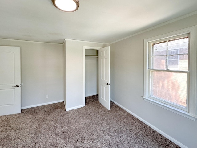 unfurnished bedroom with carpet floors, ornamental molding, a closet, and baseboards