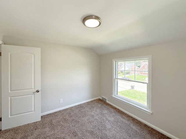 carpeted empty room featuring lofted ceiling, visible vents, and baseboards